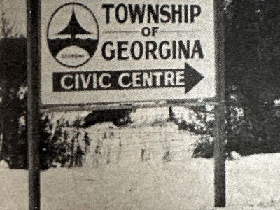 Black and white photo of a road sign pointing toward the Township of Georgina Civic Centre.